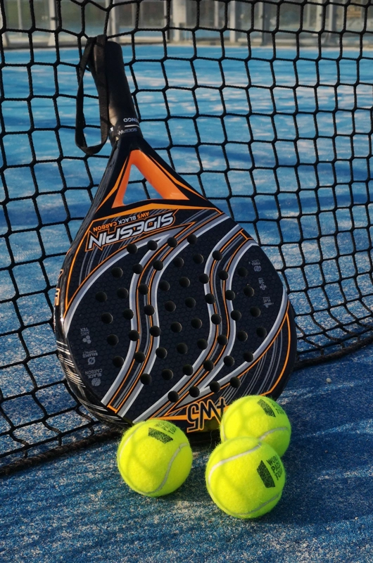 Et billede af et padelbat og tre padelbolde